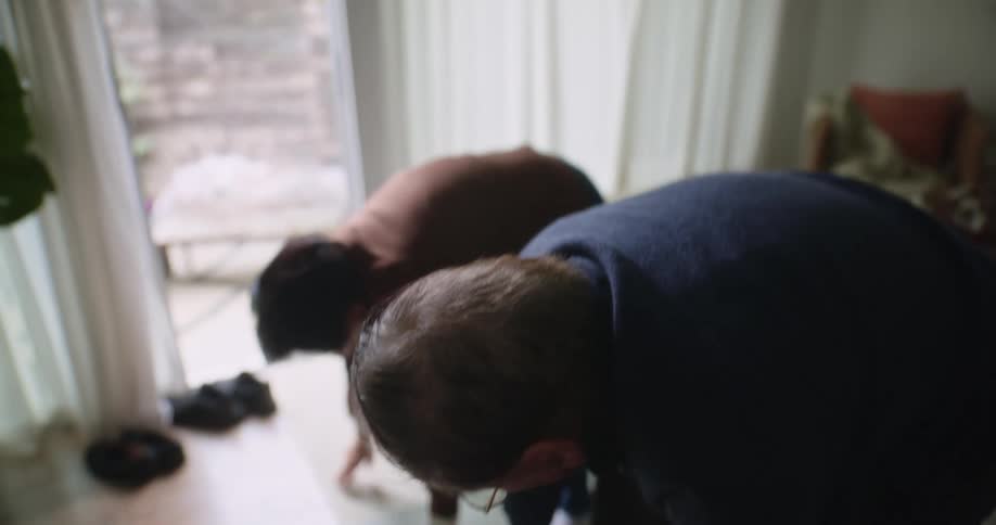 Two elderly asian people stretch in a living room