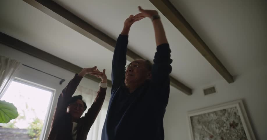 Man and woman stretching together indoors on a sunny day