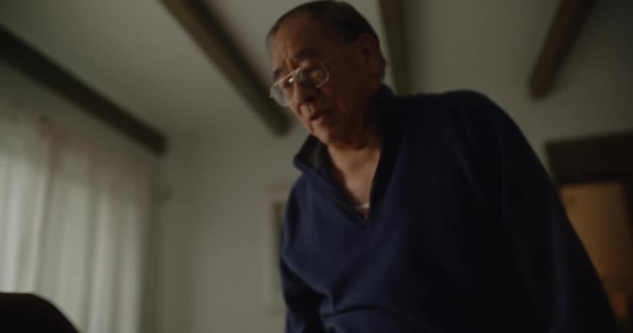 An elderly woman next to her husband in the living room doing stretching and tai chi arm movements
