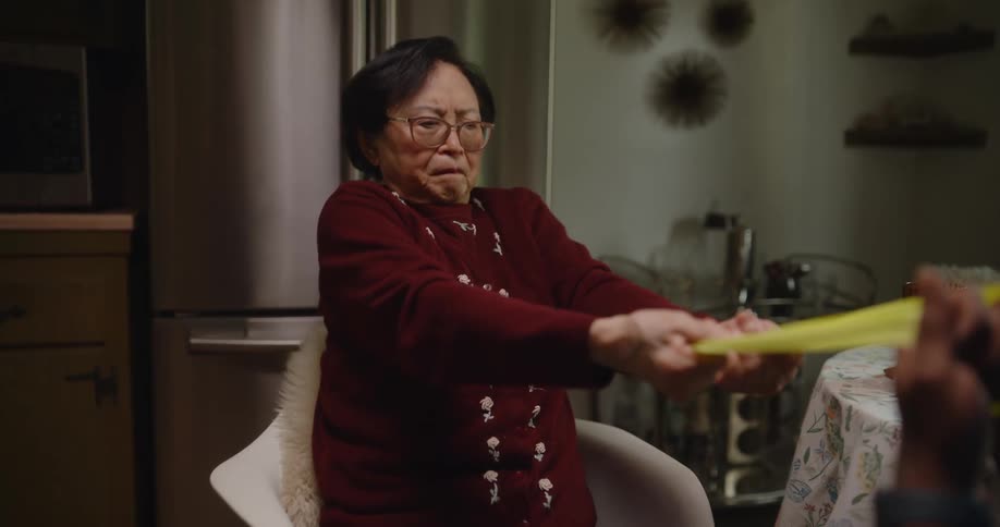 A male nurse helps an elderly asian woman with physical therapy exercises