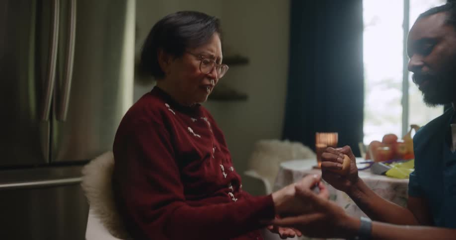 A home aid is squeezing a ball with a patient