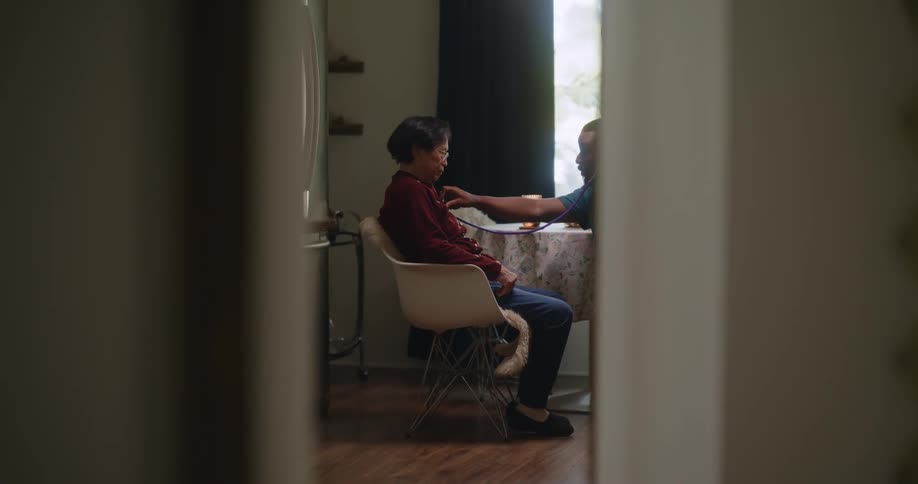 A healthcare worker listens to a female patients heart
