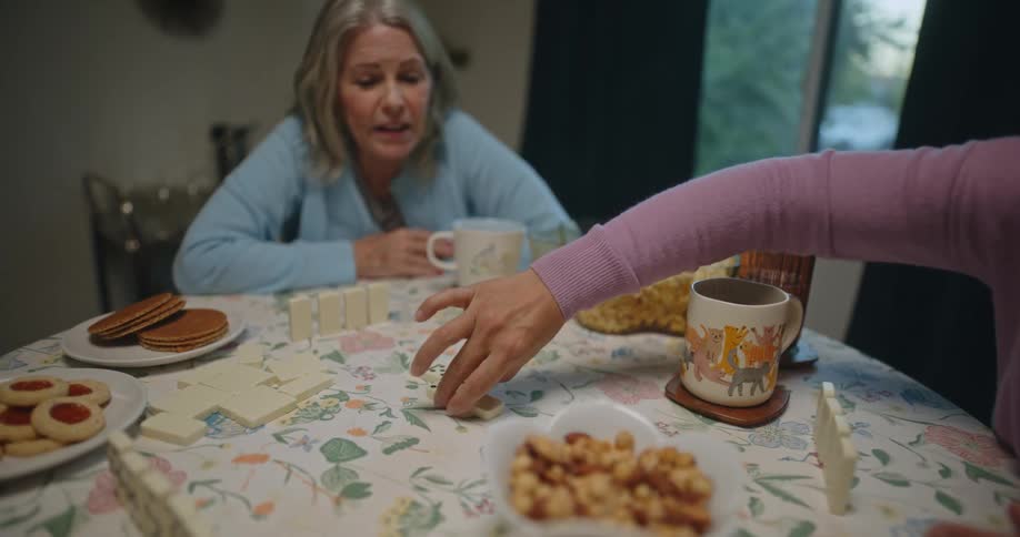 Friends sitting at a table with popcorn and cookies playing dominoes
