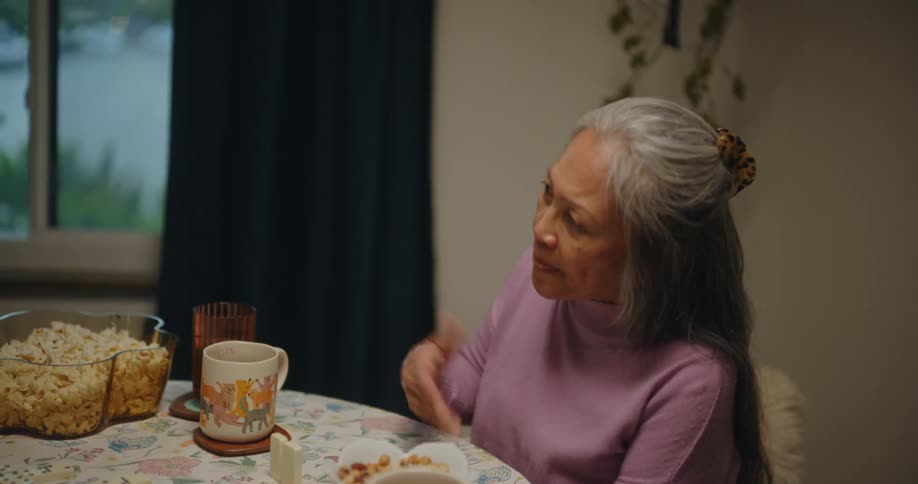 Three women play a game and talk while sitting at a table