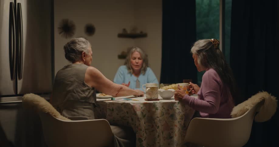 Three women are eating talking and playing a board game