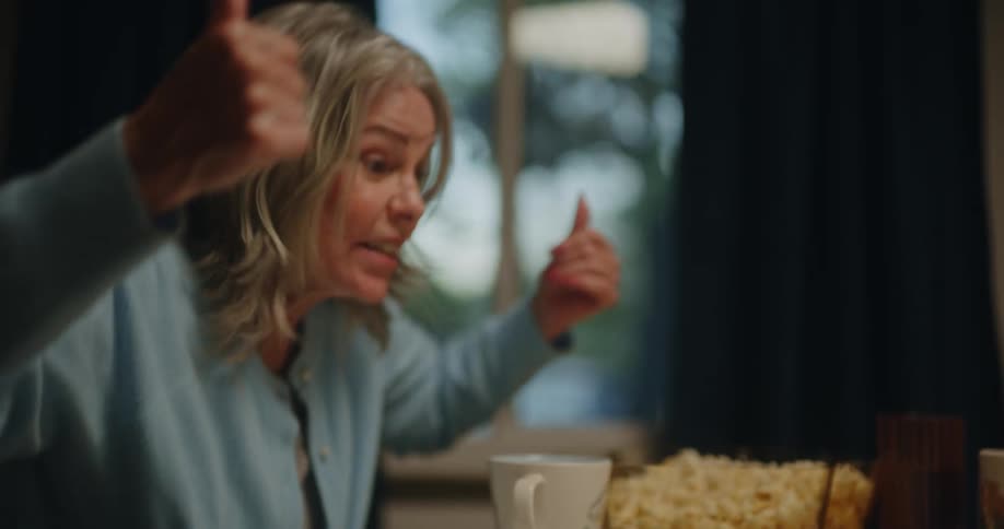 Portrait of a woman sitting at the table playing dice and raising her hands with a facial expression of surprise and then discouragement