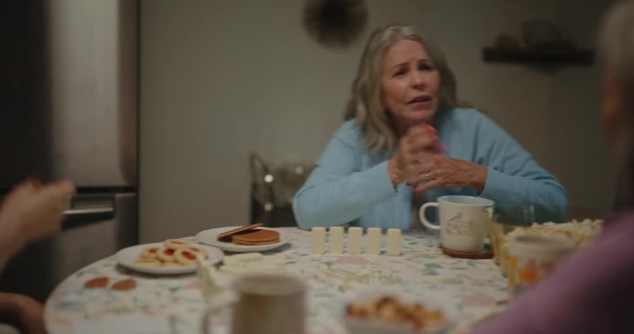 Three women laugh talk and eat at a dining room table