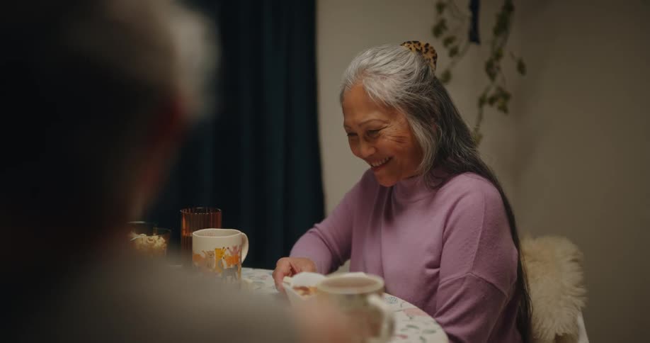 Three friends sitting at a table talking and playing dominoes