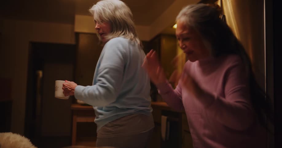 Woman holding cups gets scared by a friend at home