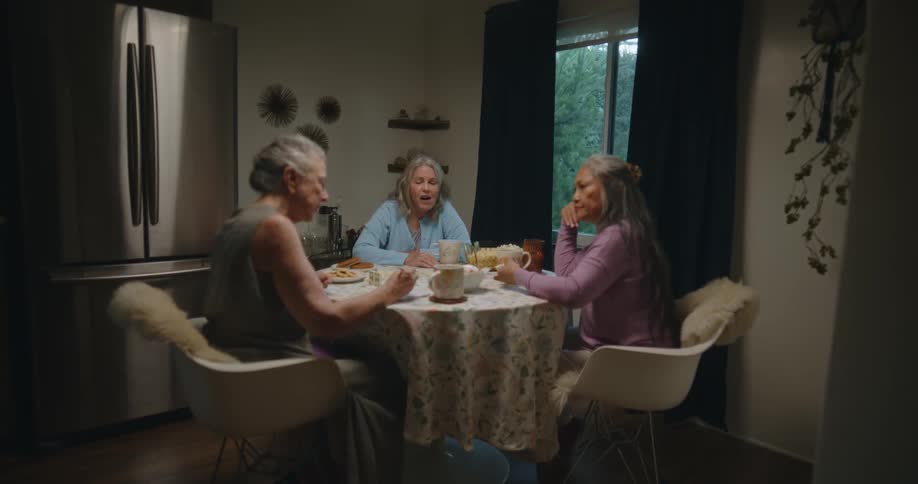 Three older women sitting at the table talking andlaughing