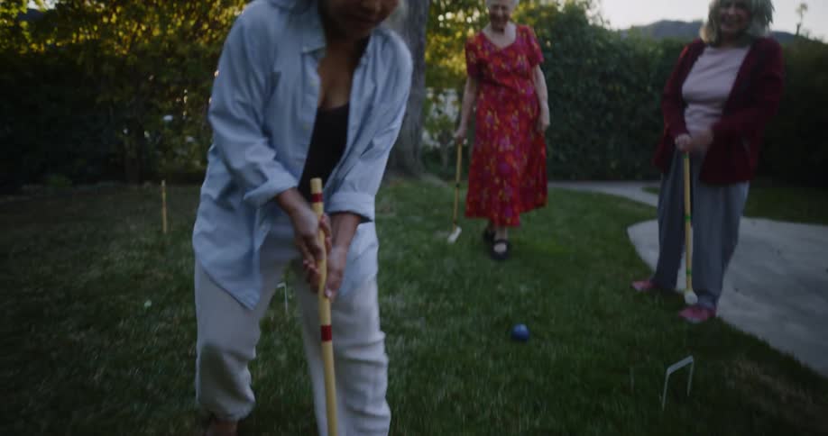 Women play croquet in the yard