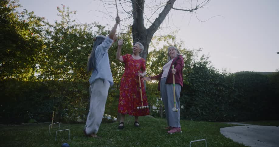 A group of elderly ladies playing crocket on the backyard at morning
