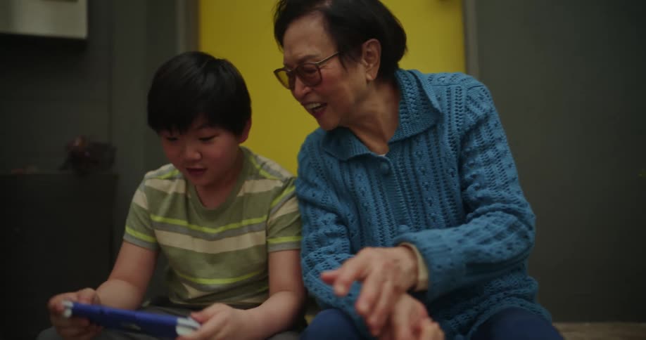 A grandmother watches her grandson play video games