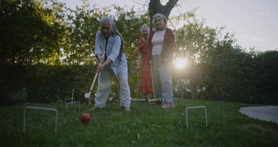Three friends are playing croquet on a summer day at sunset