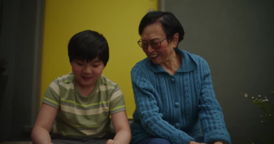 A grandmother watches her grandson play a video game