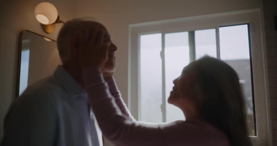 A woman enjoys rubbing a mans face in a bathroom