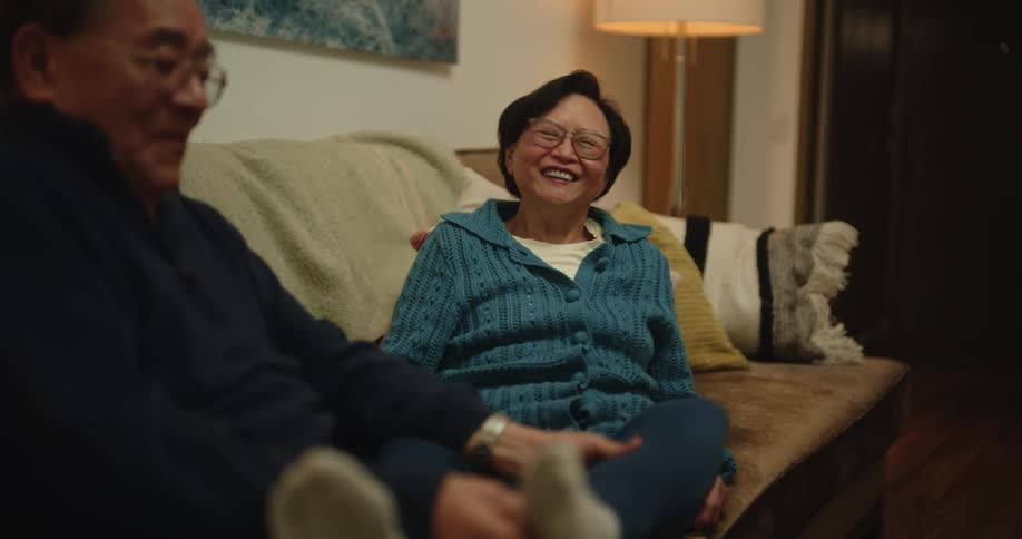 Woman smiles while her husband massages her legs and feet in the living room