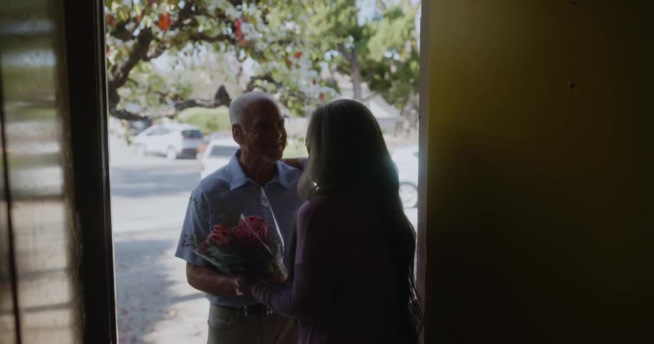 Man greets his wife and gives her a bouquet of flowers