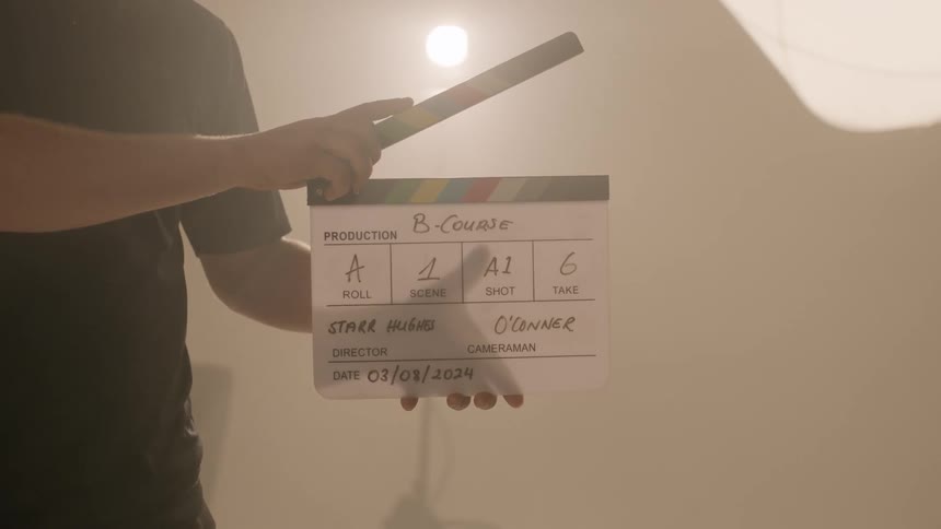 A crew member closes the clapperboard