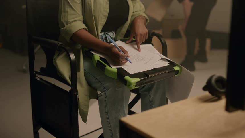 Hands of a woman sitting on a chair scribbling on a printed paper