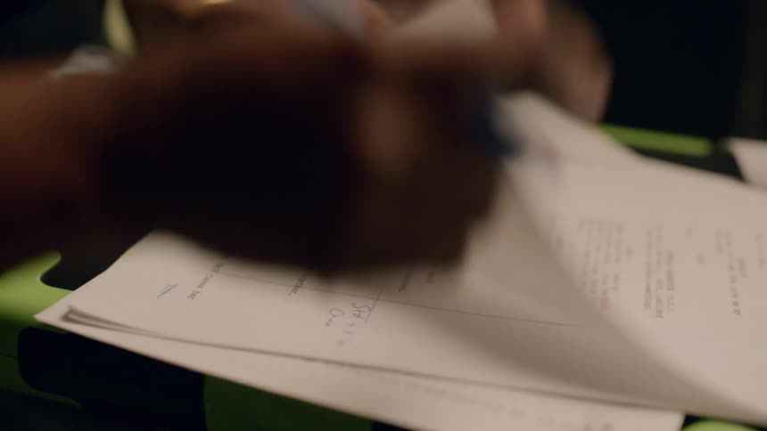 A person is flipping through papers and writing on them