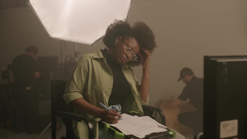 A black woman reads a script and crosses words out