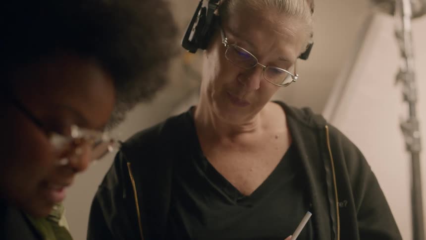 Portrait of two women talking and taking notes inside a studio