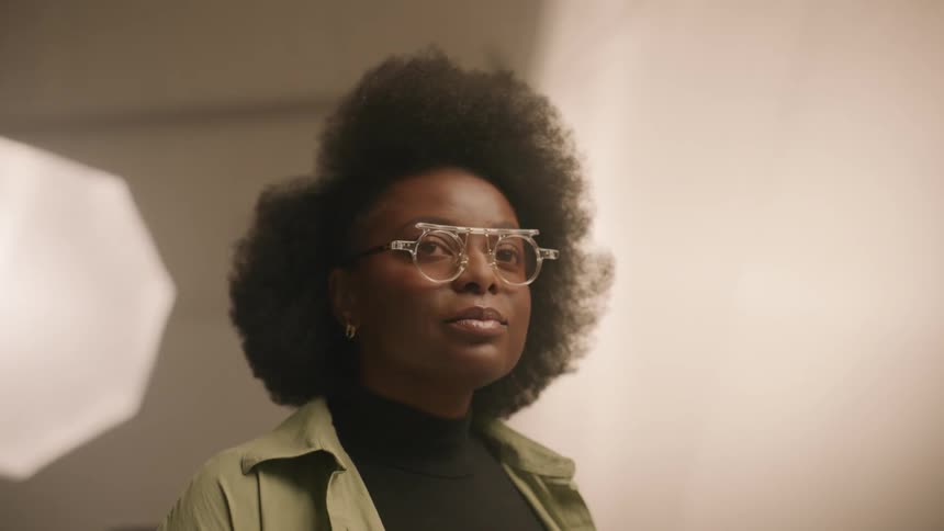 A black woman stands in a room and thinks