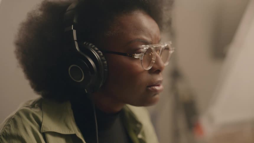 Woman sitting down and wearing headphones while deeply thinking