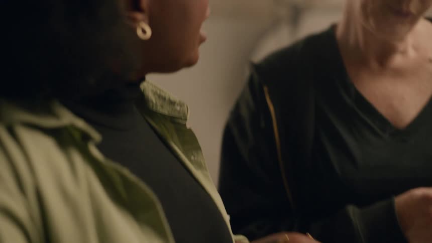 Two women inside a studio talking while one of them takes notes with a pen