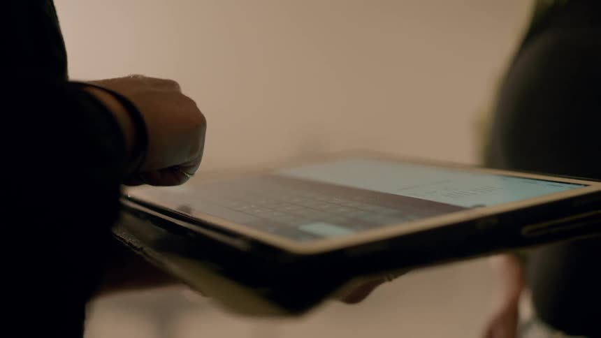 Closeup of a womans hands typing on a tablet