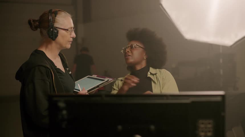 Woman is talking to a group of people indoors wearing headphones
