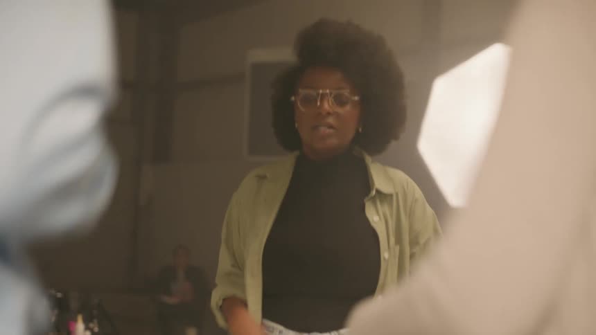 Woman inside a studio jumping and moving her arms facing two other people
