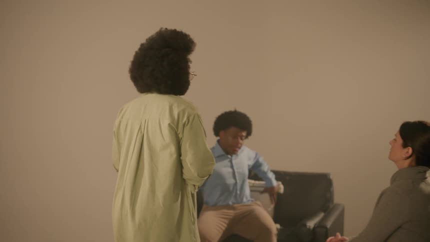 Woman talking to two people who are sitting on the sofa in a studio