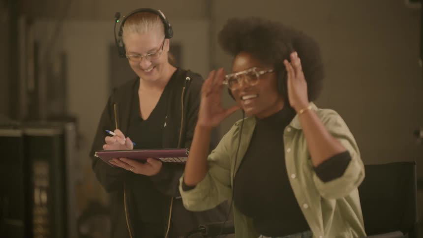 Two women laugh together in a studio