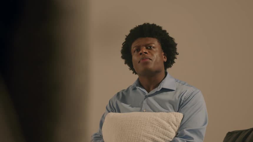 A black man sits in a room and speaks