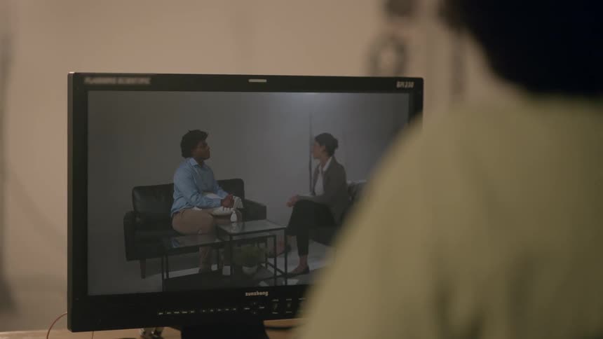 A person watches a monitor showing two actors doing a scene