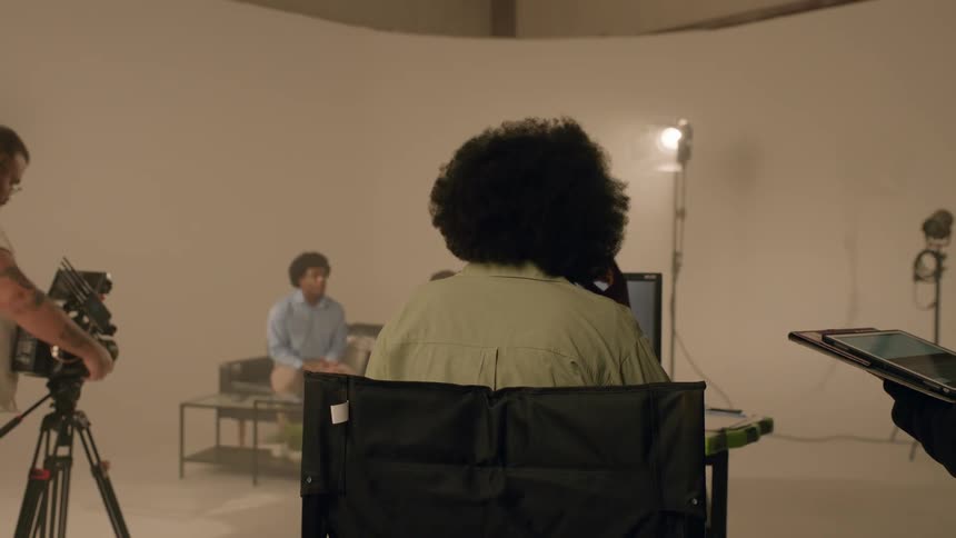 Group of people in a studio with a filmmaker recording a scene of other people around