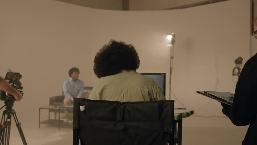 People inside a studio where a scene of a man talking is being recorded