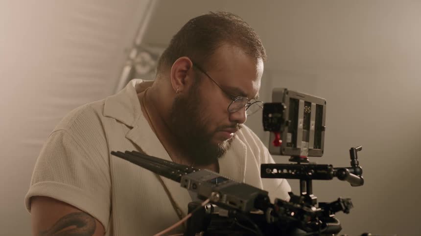 Concentrated filmaker man with his professional video camera in a studio
