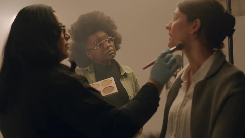 People talk while makeup is being applied to a woman