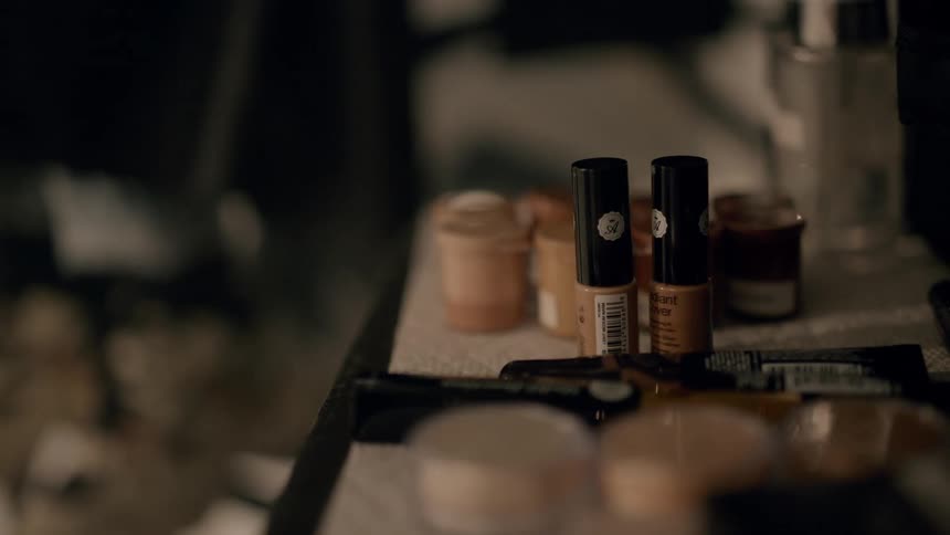 A person picks up a bottle of make up
