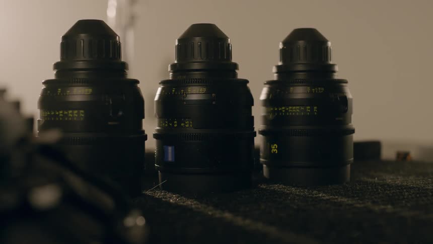 Three professional camera lenses on a bench
