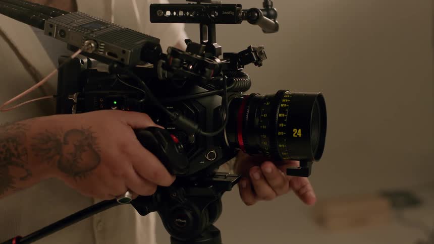 Closeup of a mans hands adjusting the lens of a professional video camera