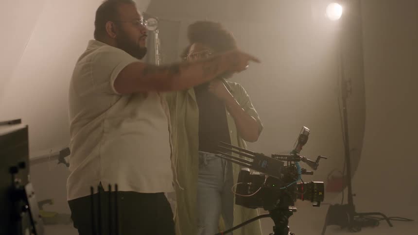 A man and a woman have a focused conversation in a film studio