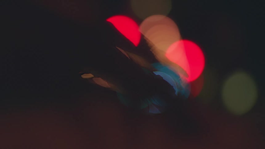 A blurred hand moves slowly in front of blurred lights