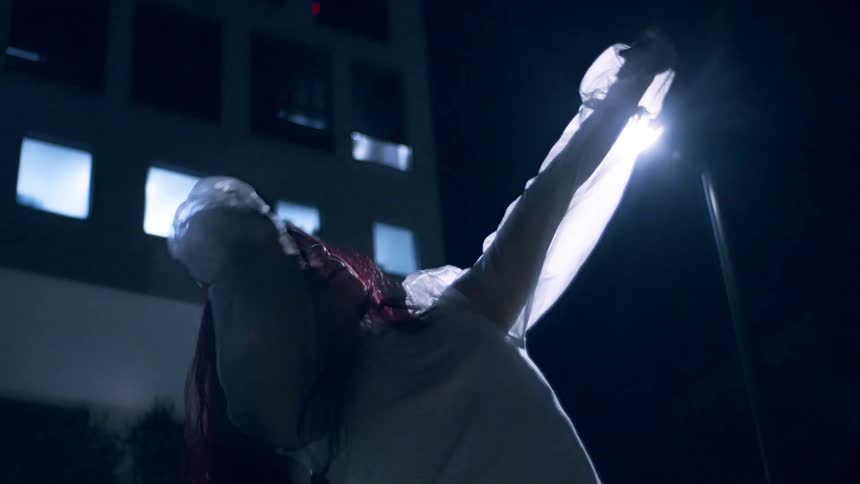 Young woman through the streets inside the city at night dancing artistically