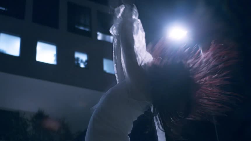 Woman in performance and solo dancing with her hands up and moving her hair while outdoors at night in the city