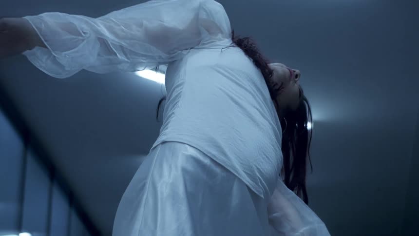 Woman dancing by herself in a room while wearing a white dress