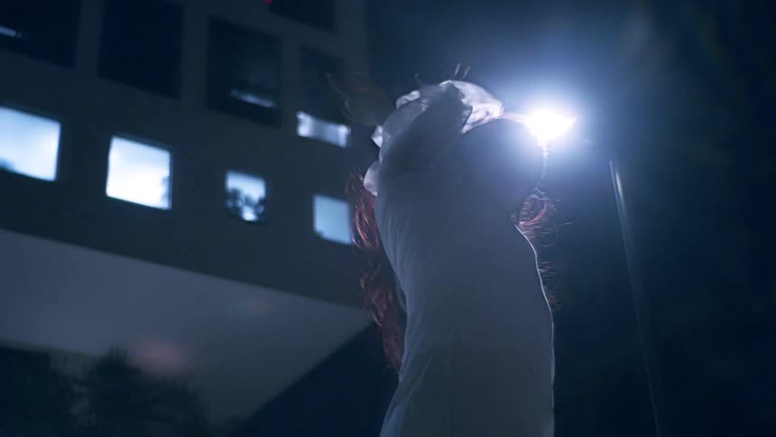Young woman in a white dress dancing in an outdoor setting at night